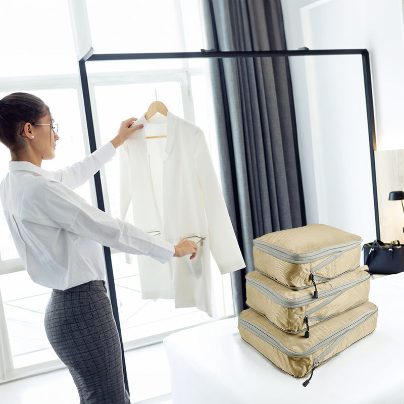Traveler packing folded clothing beside a beige compression packing cube set