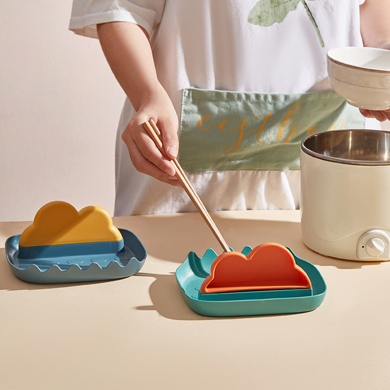 Orange and yellow utensil rests beside a countertop cooker during meal prep