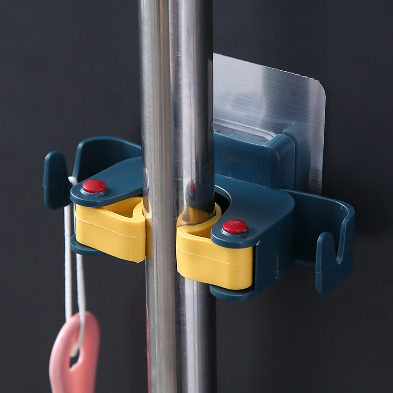 Dark blue adhesive wall clip gripping a silver cleaning-tool handle with an accessory on the side hook